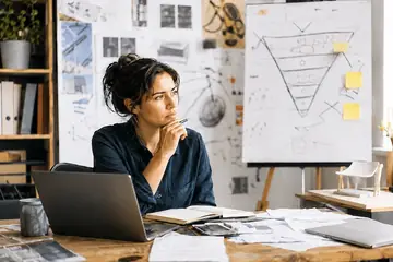 Une femme réfléchit devant un schéma de pyramide