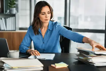 Une femme trie une pile de dossiers sur son bureau
