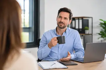 Un homme discute avec une interlocutrice à son bureau